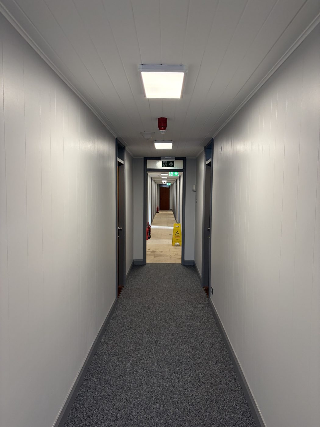 The same office corridor after decoration, painted white with grey trim