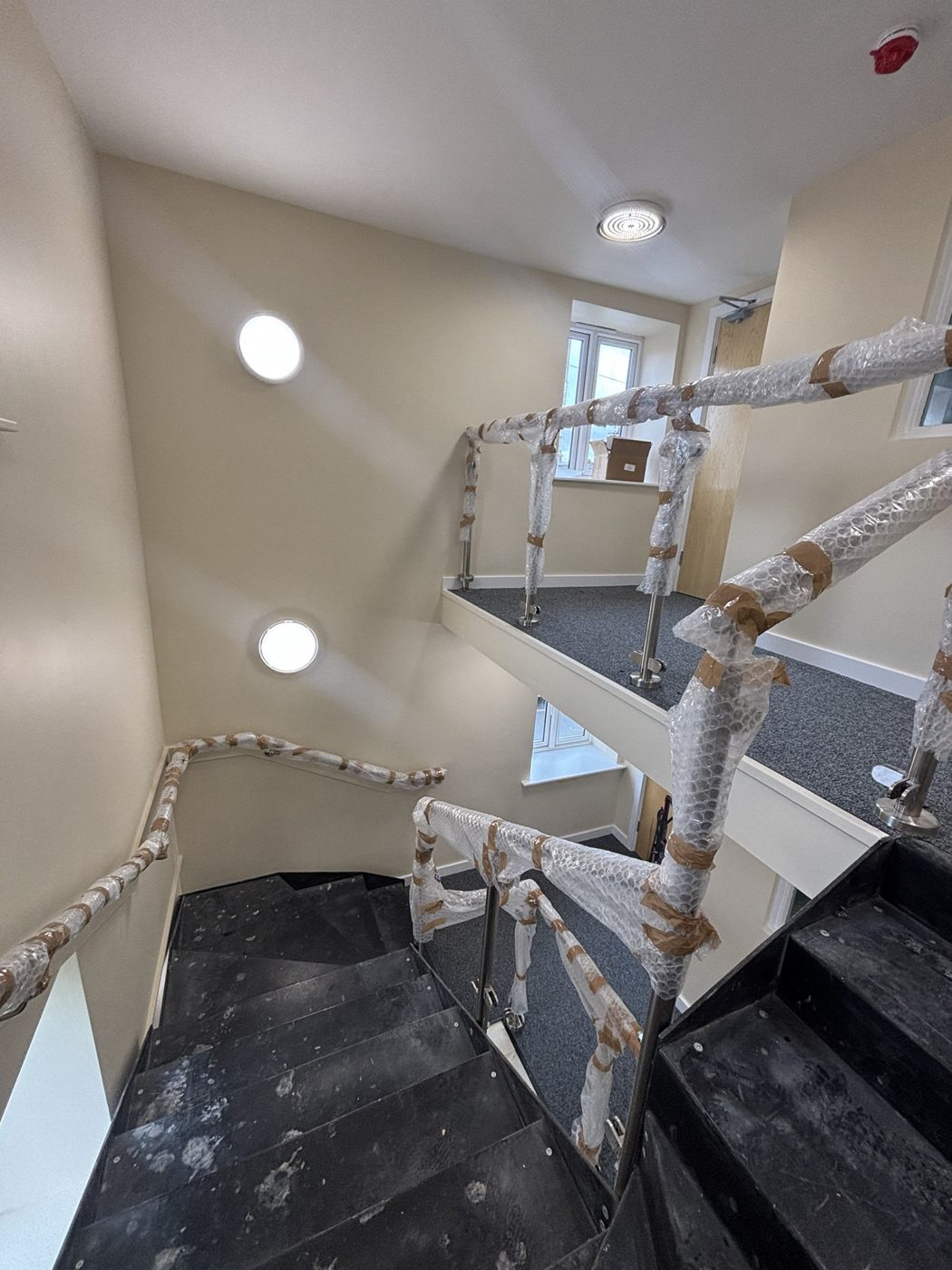 Stairwell mid-project with handrails wrapped for protection